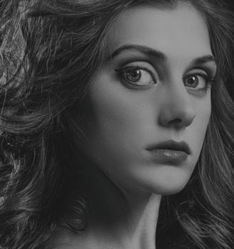Close-up black and white portrait capturing a woman's expressive gaze and intricate details.