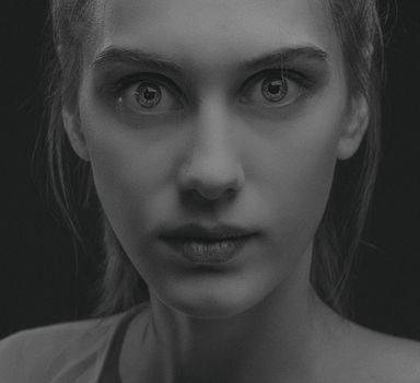 Grayscale portrait of a young woman with a serious expression, highlighting facial details and emotions.