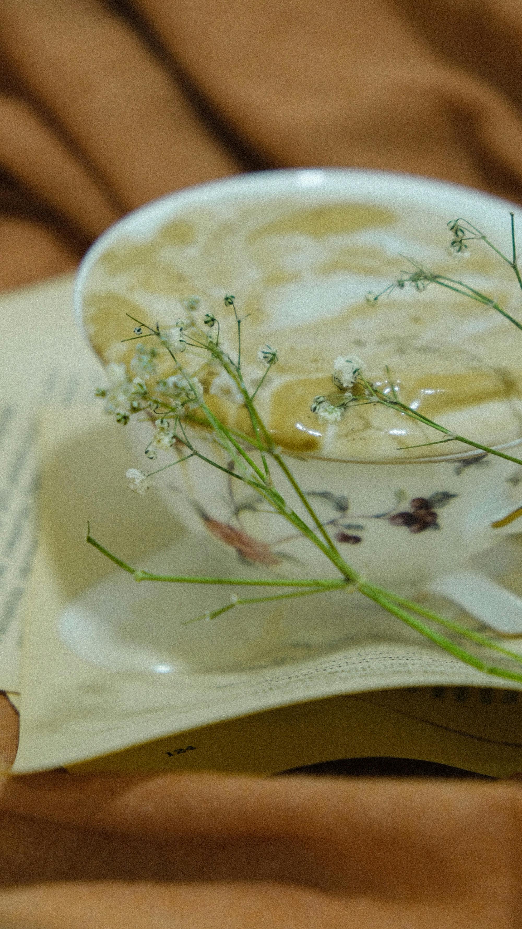 Close-up of a decorative coffee cup adorned with baby's breath on a warm fabric background.