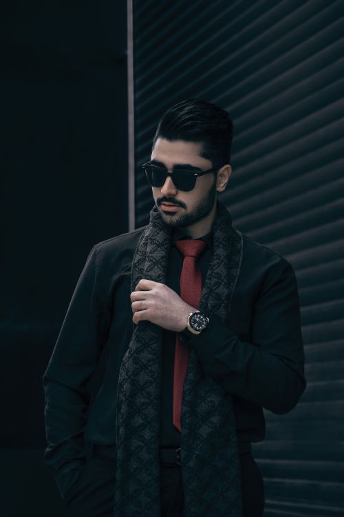 Free Fashionable man in sunglasses and scarf, posing confidently in an urban setting. Stock Photo