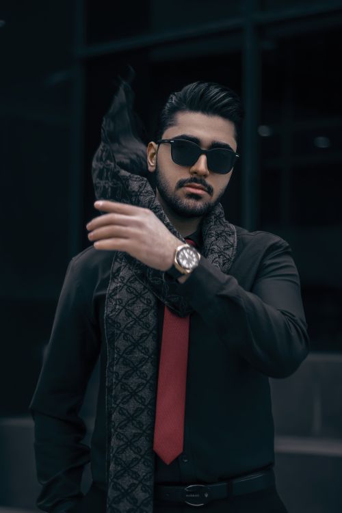 Free Portrait of a fashionable man in sunglasses and scarf against a dark background. Stock Photo