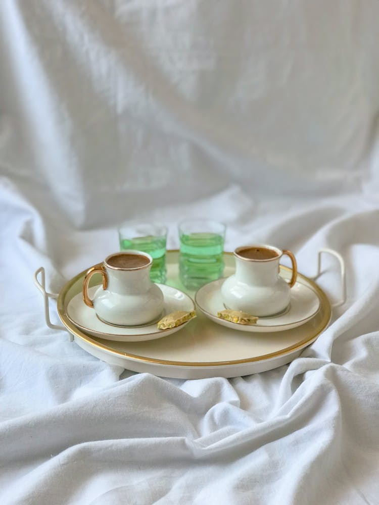 Tray With Coffee Cups On White Bedding