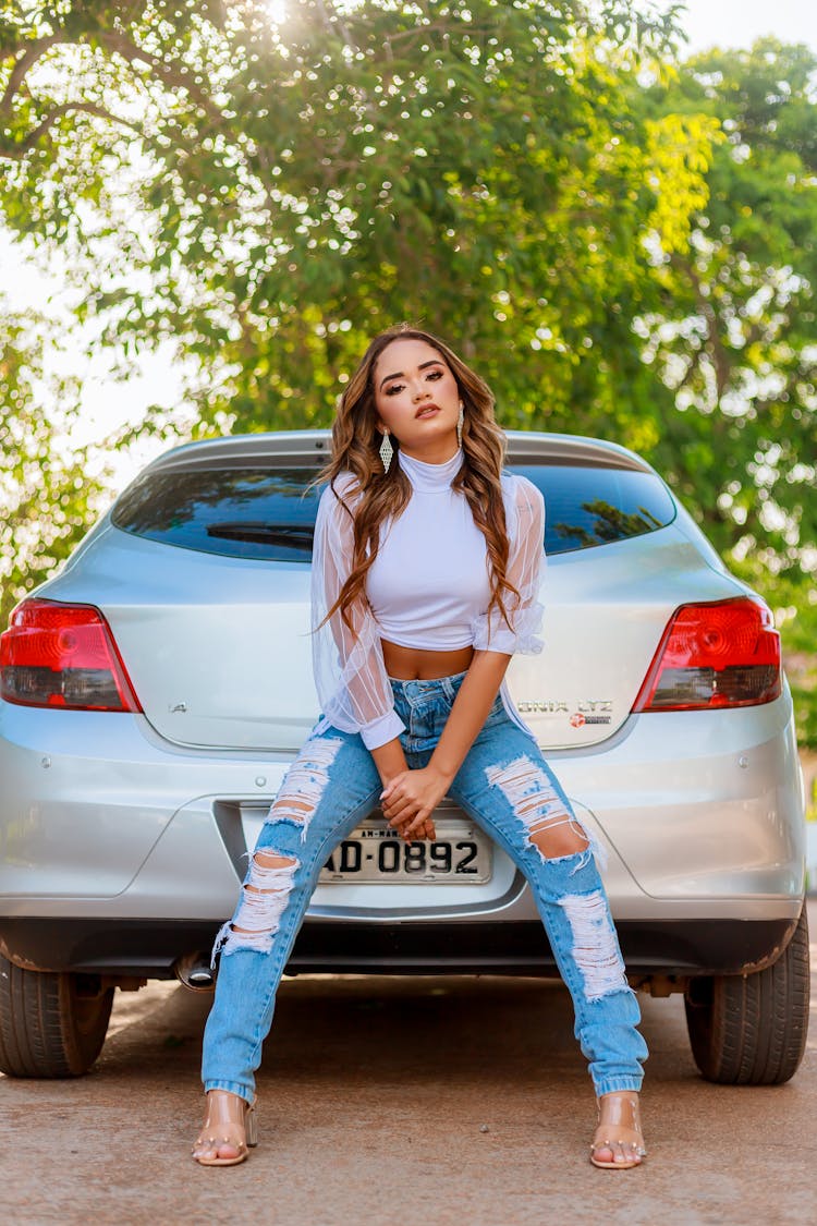 A Woman Sitting A Car Rear Bumper