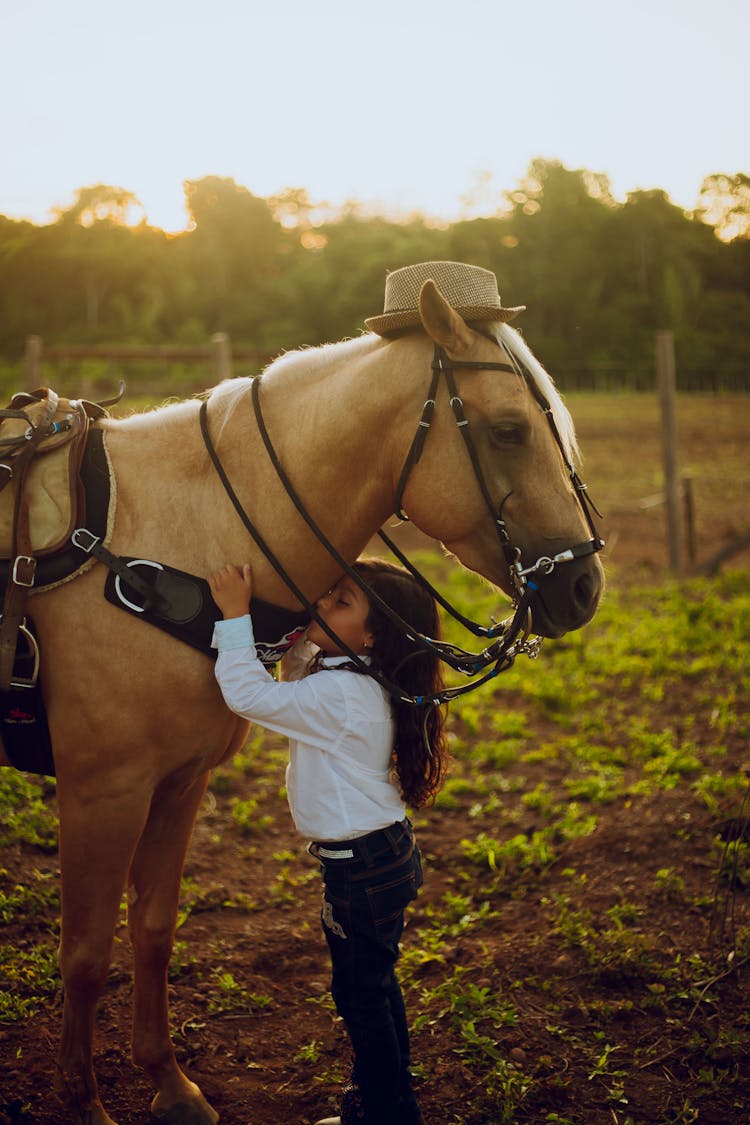 Little Girl Hugging Horse Wearing Hat