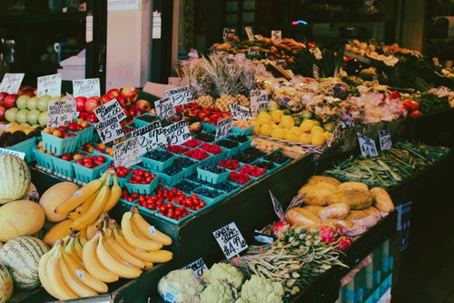 Free Colorful fruit and vegetable market stall displaying a variety of fresh produce with visible price tags. Stock Photo