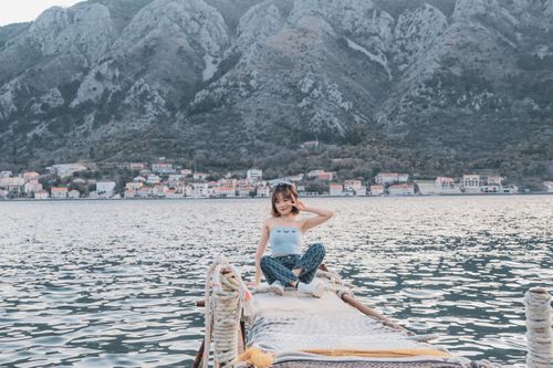 Free Young woman enjoying a serene moment on a dock with a mountain view in Kotor, Montenegro. Stock Photo