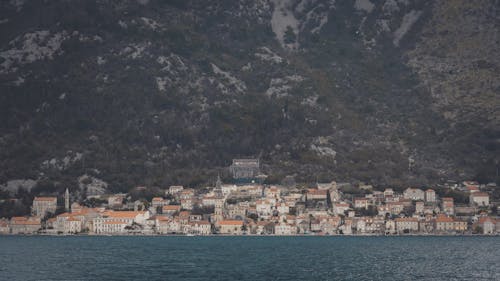 City Buildings on Foot of Mountain Along a Body of Water