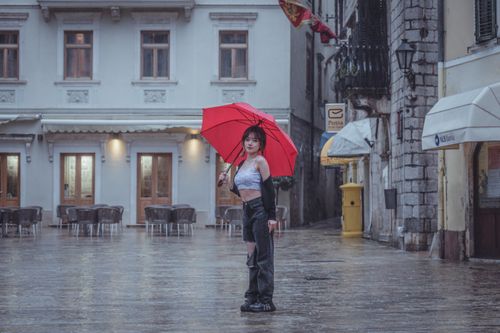 Free Portrait of an Asian woman with a red umbrella in rainy Kotor, Montenegro. Stock Photo