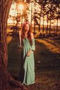 Woman in Gray Dress Standing Beside Brown Tree