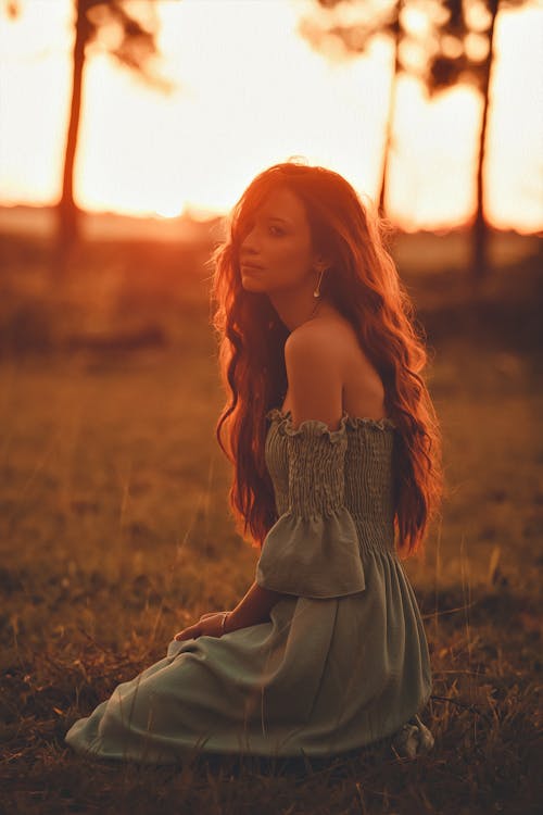 A Woman Sitting on the Grass Field