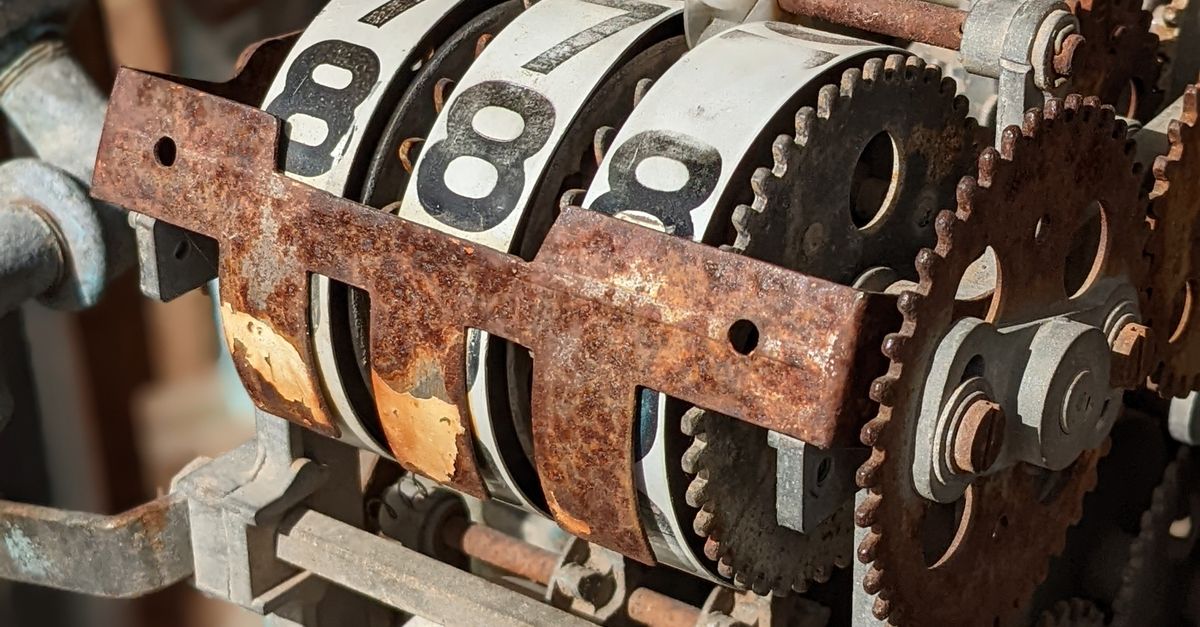 Photo by Curraw K Close-up of rusty mechanical gears with numbered display wheels in vintage machinery setup.