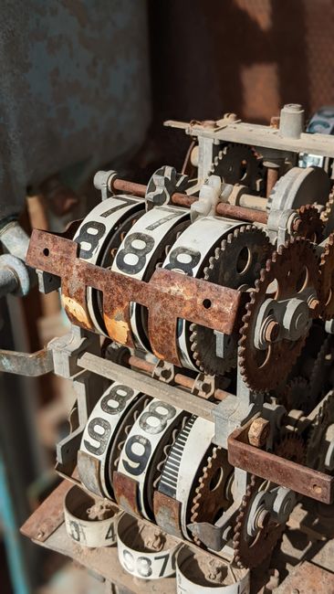 Photo by Curraw K Close-up of rusty mechanical gears with numbered display wheels in vintage machinery setup.