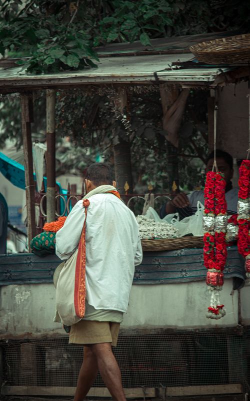 Free A man in traditional attire shops at a street stall in India selling floral garlands. Stock Photo
