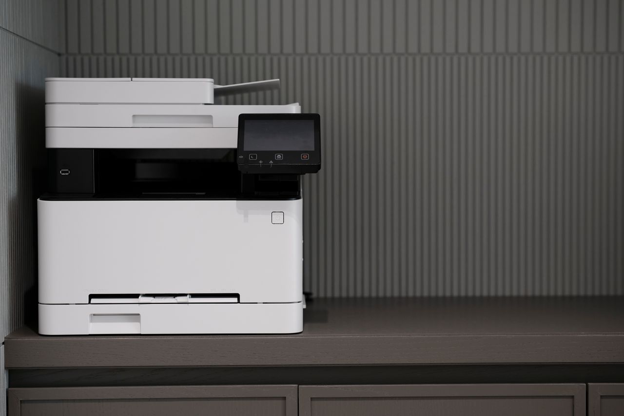 A sleek, modern printer situated on a minimalist office desk with a textured background.