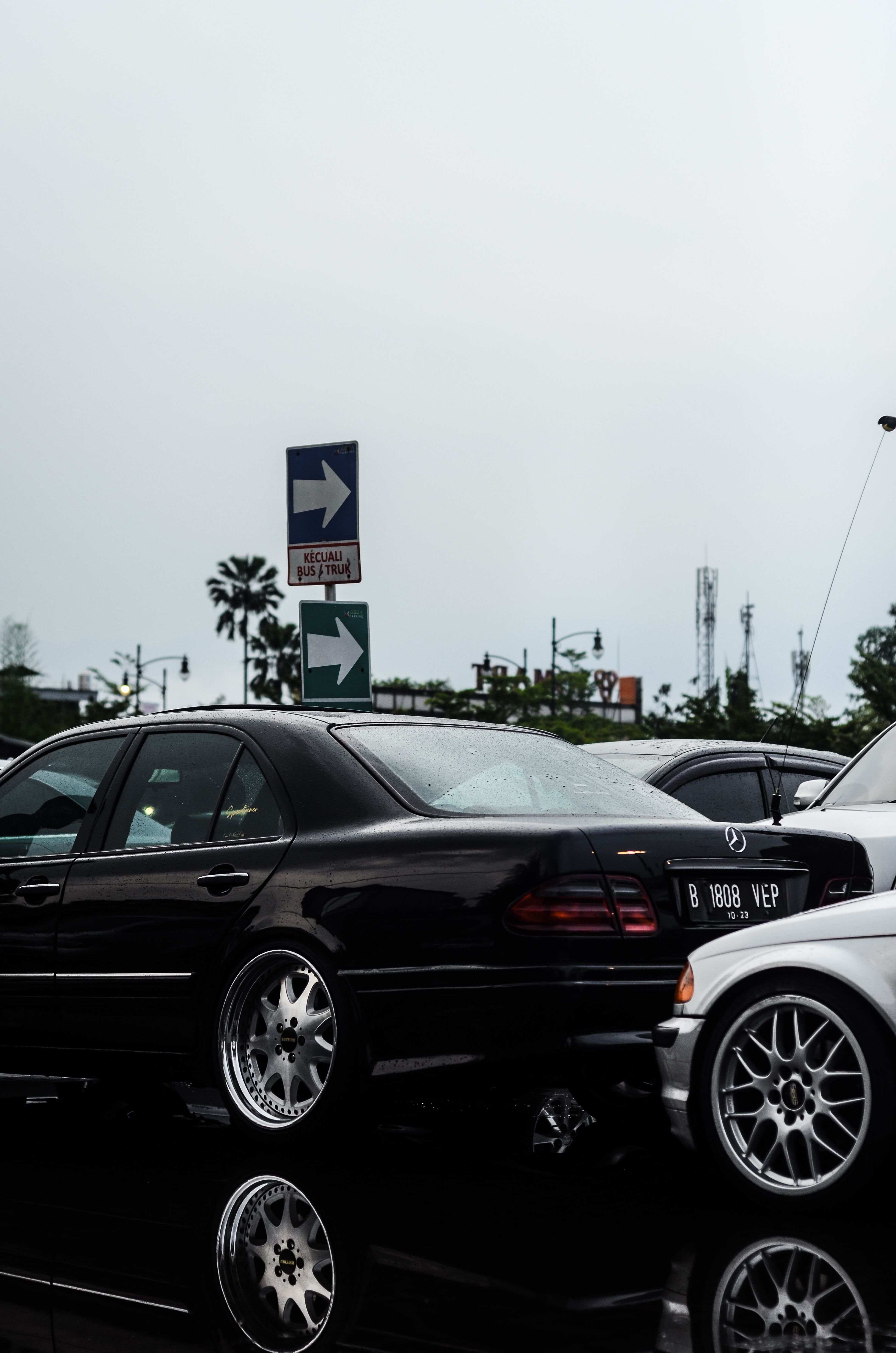 Elegant black sedan in a parking lot with reflections, showcasing luxury and style.
