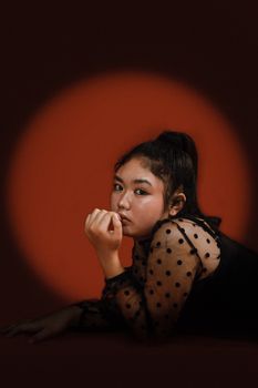 Studio portrait of a stylish young Asian woman with a thoughtful expression, showcasing fashion and elegance.