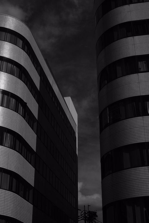 Free Dramatic black and white photo of modern city buildings under a moody sky. Stock Photo