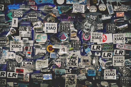 A vibrant urban wall adorned with a mix of stickers and graffiti, showcasing diverse street art.