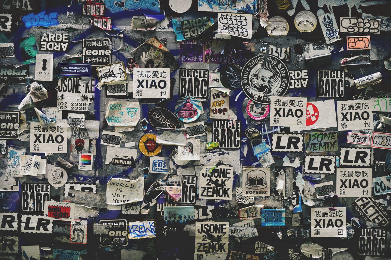 a vibrant urban wall adorned with a mix of stickers and graffiti showc