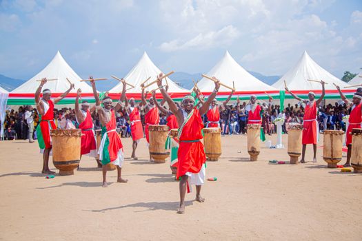 Vibrant performance of Burundian drummers in colorful traditional attire with large drums and white tents.