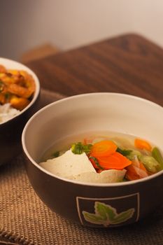 Warm and nutritious homemade vegetable soup with tofu in a ceramic bowl, perfect for a healthy meal.