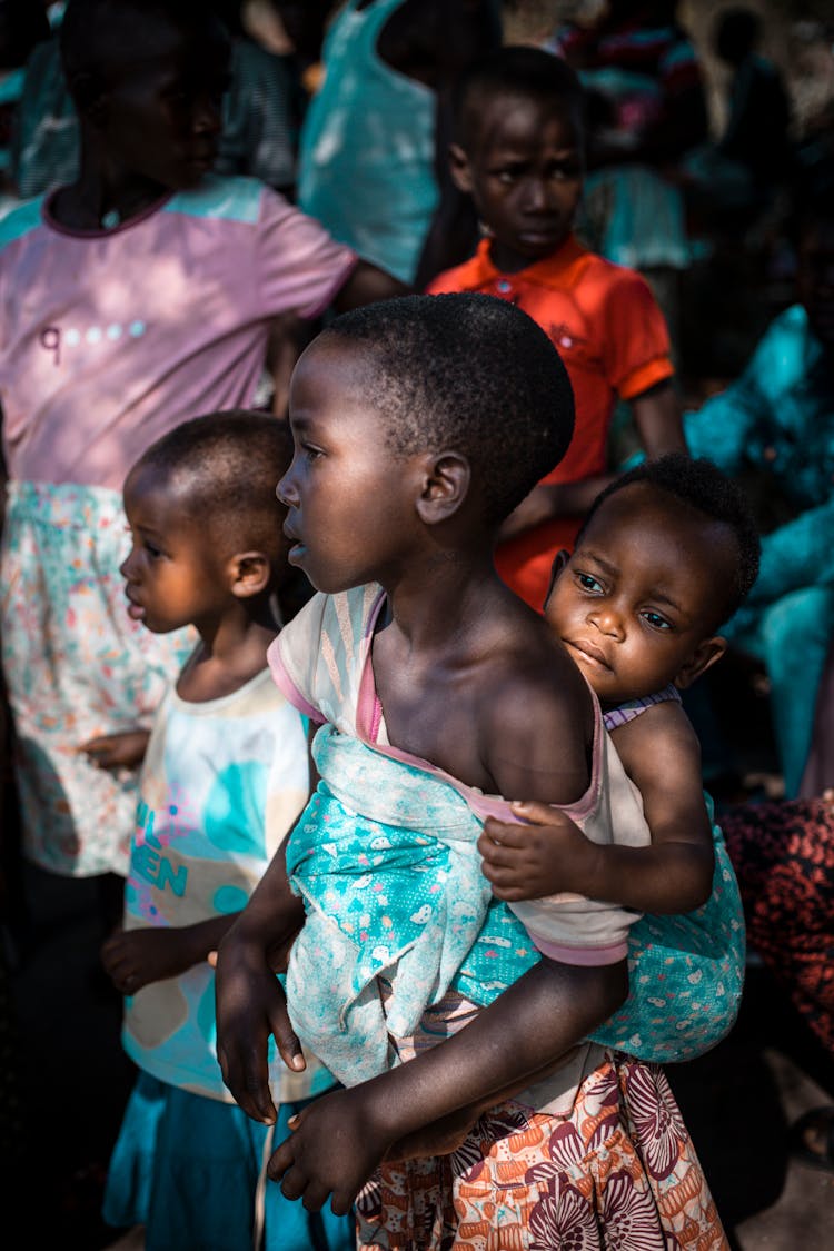 Little Girl Carrying Toddler On Her Back