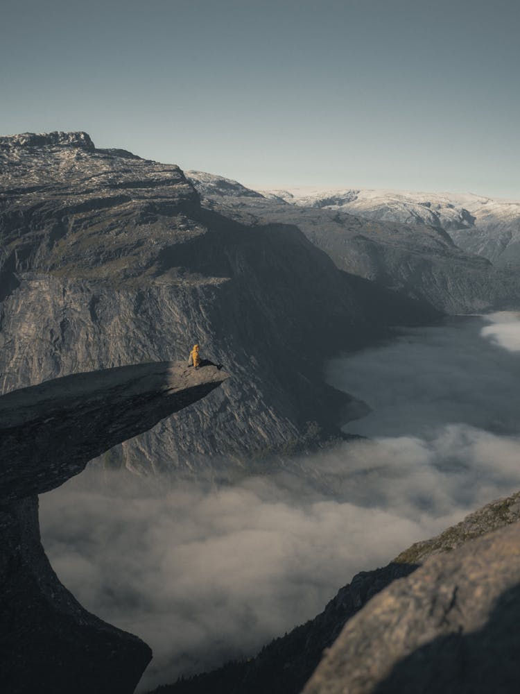 Person Sitting On The Edge Of Troll Tongue Rock Formation