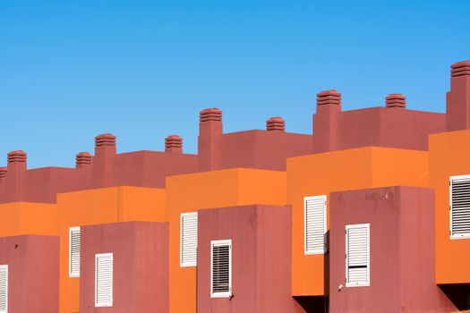 Modern architectural building with geometric shapes and vibrant colors under a clear blue sky.