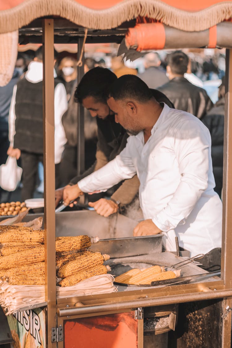 Men Selling Grilled Corn Cobs On The Street