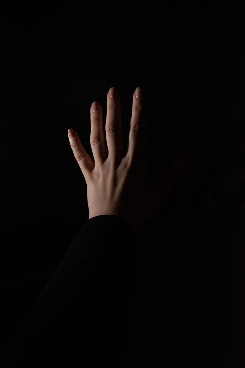 Free Minimalist close-up of a hand against a black background, highlighting texture and form. Stock Photo
