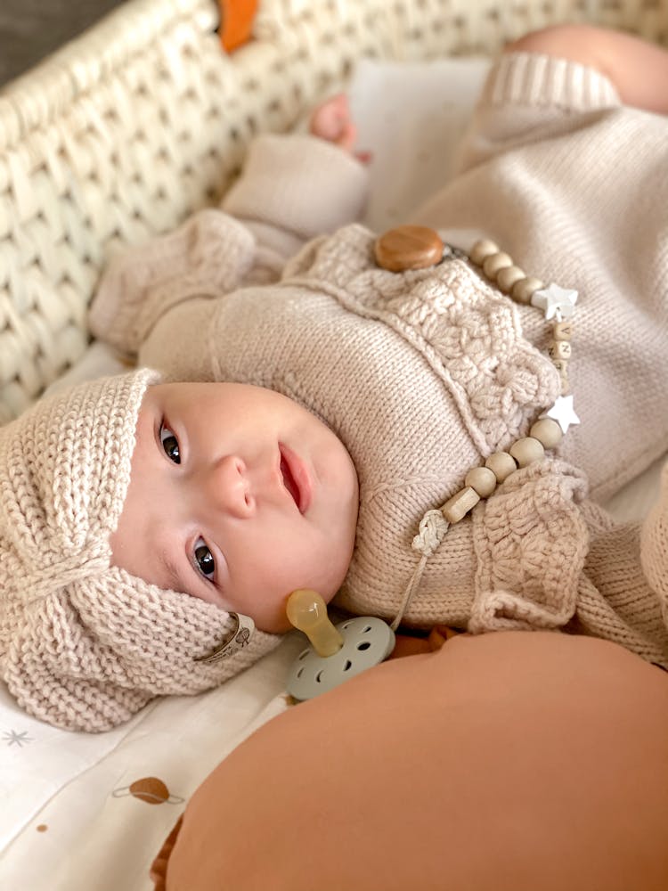 Baby In White Knitwear Lying In Woven Basket