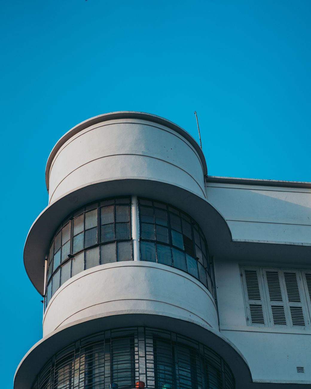 A striking Art Deco building facade with round corner windows against a clear blue sky.. pexels, striking, deco