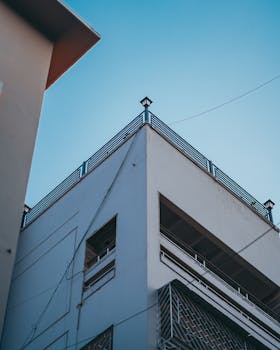 A modern urban building captured from a low angle against a clear blue sky.