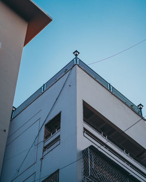Free A modern urban building captured from a low angle against a clear blue sky. Stock Photo