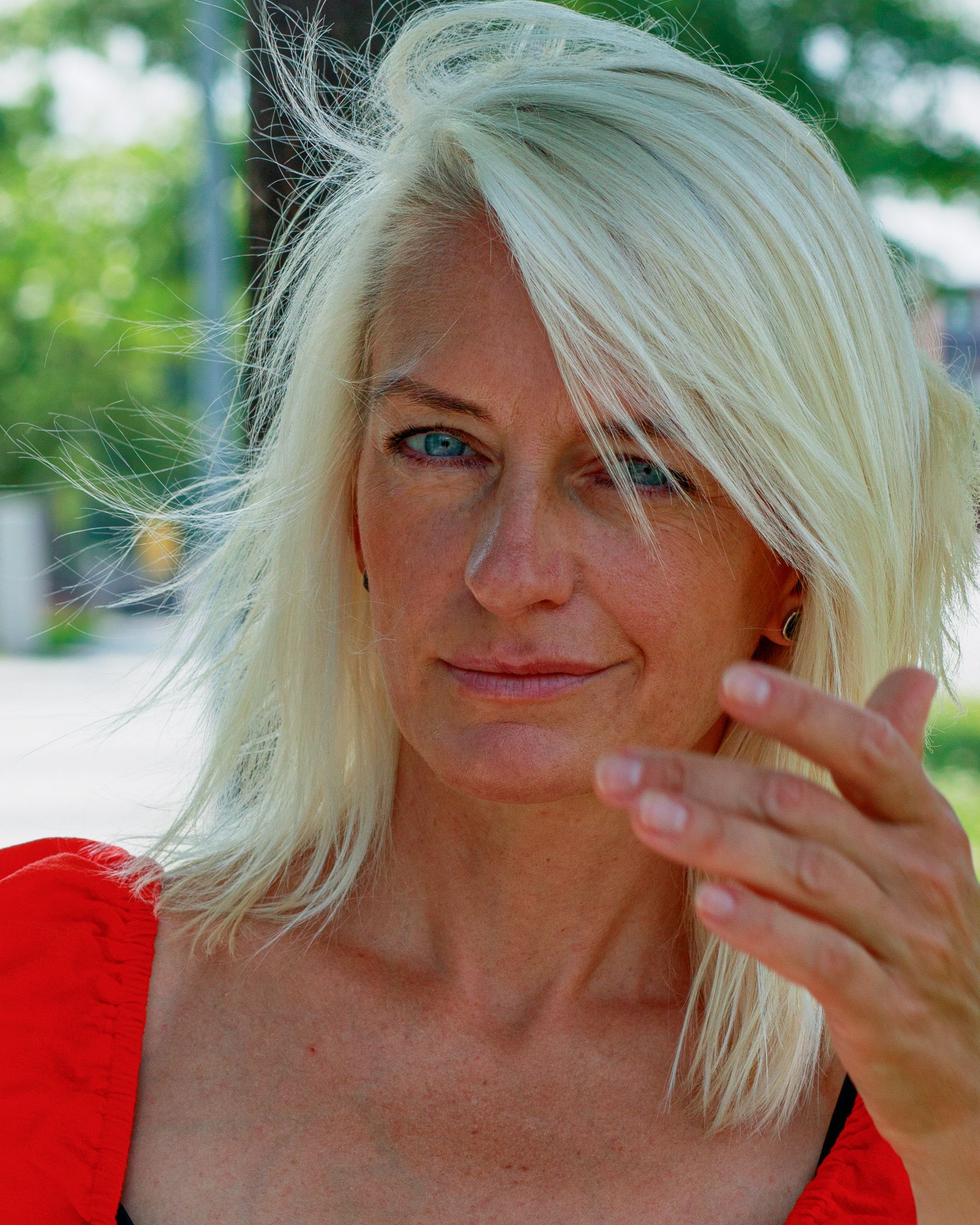 Portrait of a woman with white hair and blue eyes, captured outdoors in a confident pose.