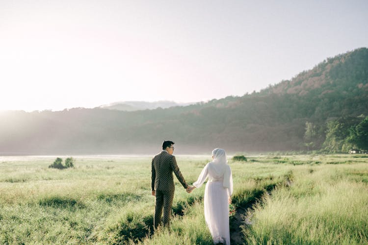 Couple Walking On Grass Field