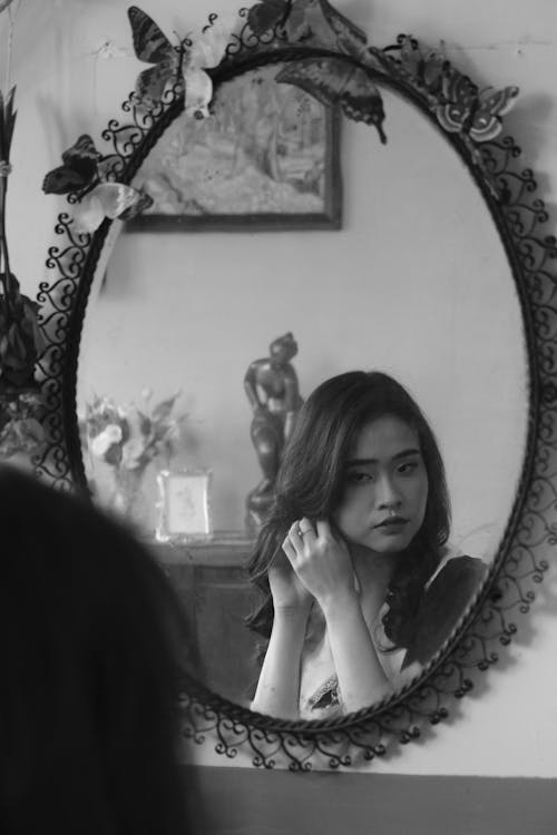 Grayscale Photo of Woman Using Mirror