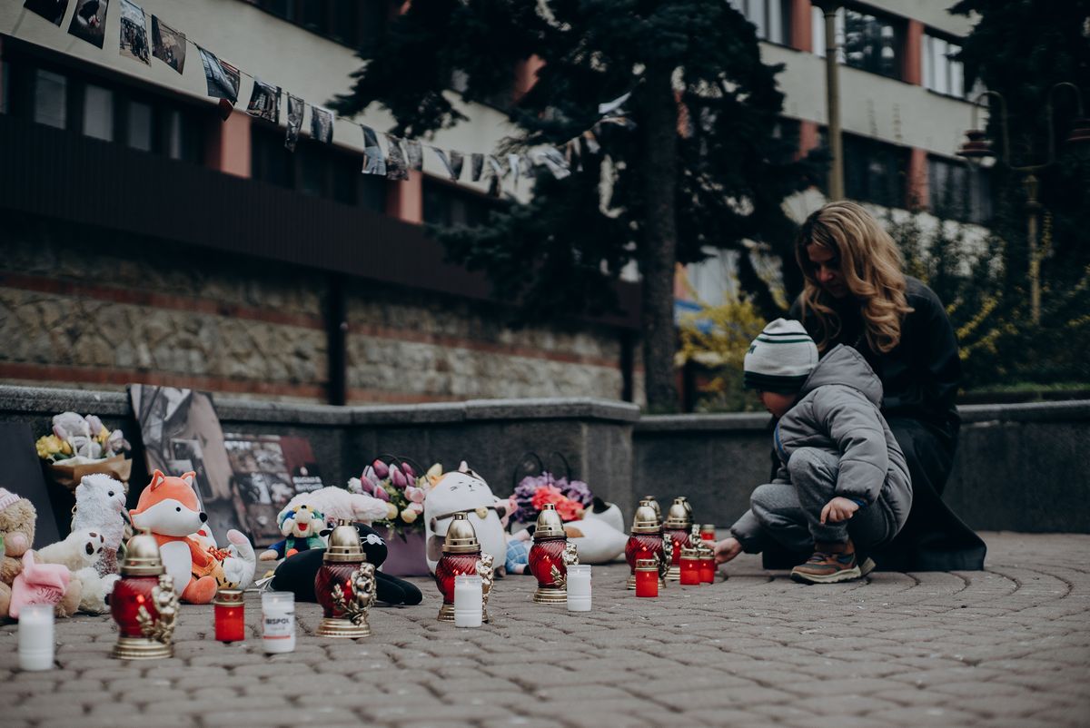 Мати з дитиною біля меморіалу зі свічками в Україні