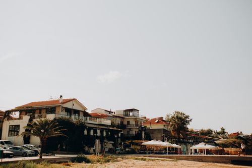 Free Picturesque Greek seaside with traditional architecture and palm trees under clear skies. Stock Photo