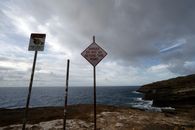 Red and White Text Sign on the Shore