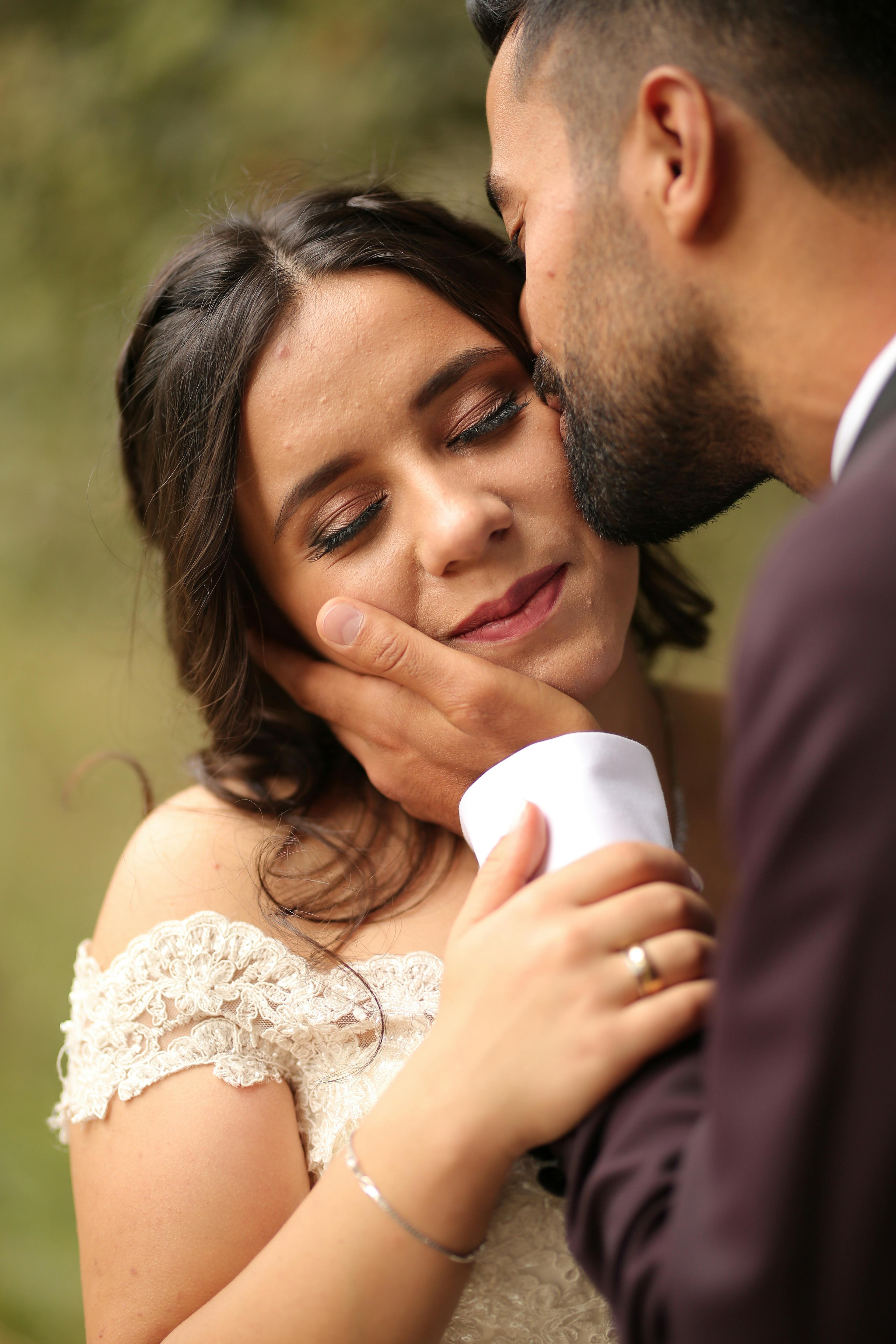 An intimate moment between a bride and groom outdoors, expressing love and affection.