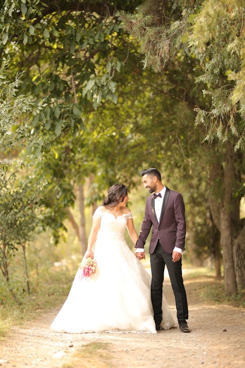 A Couple Holding their Hands while Standing In Between Trees