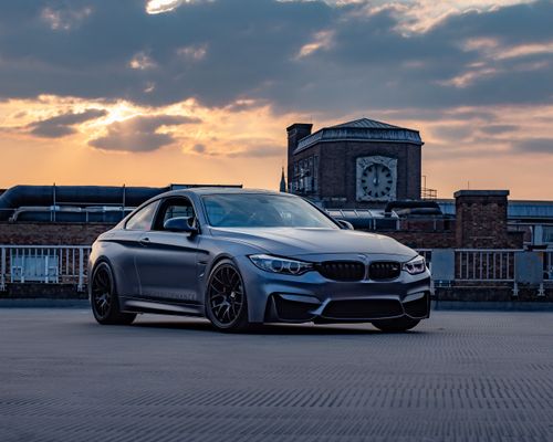 Free A sleek luxury sports car parked on a rooftop at sunset with industrial backdrop in Leicester, UK. Stock Photo