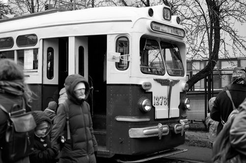 Free Black and white photo of commuters walking past a classic tram in an urban setting. Stock Photo