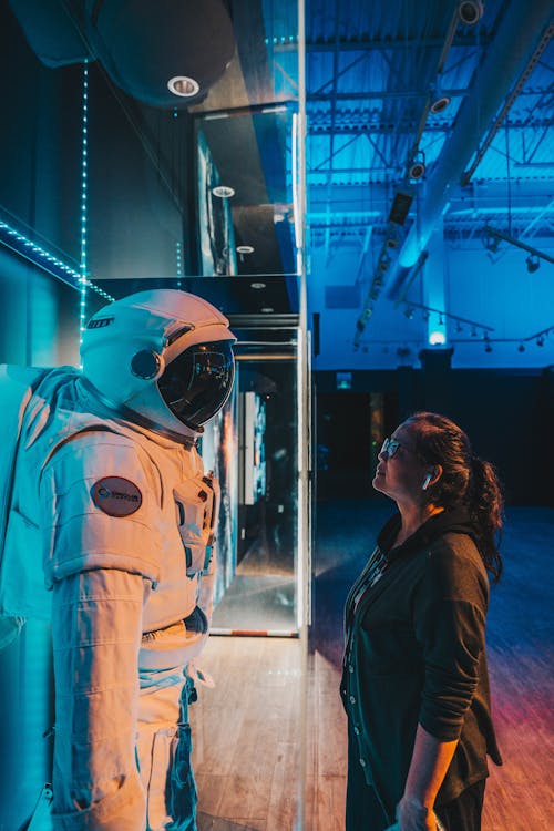 Woman in Black Jacket Looking at Spacesuit 