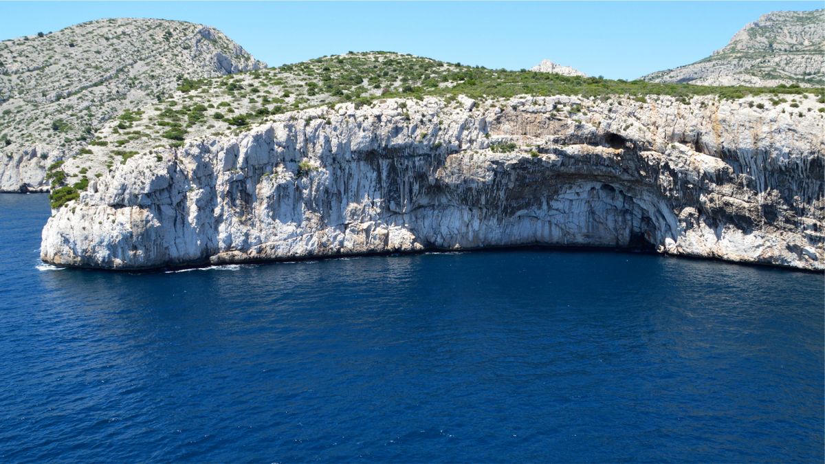Majestic sea cliffs with lush greenery meeting turquoise Adriatic water