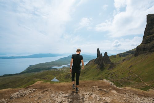 崖の上に立っている黒いtシャツを着ている男