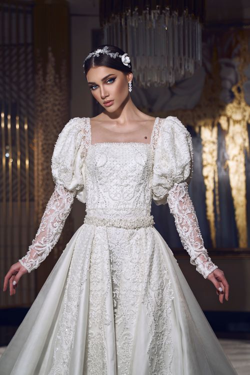 Free A stunning portrait of a young bride in an elegant white lace dress indoors. Stock Photo