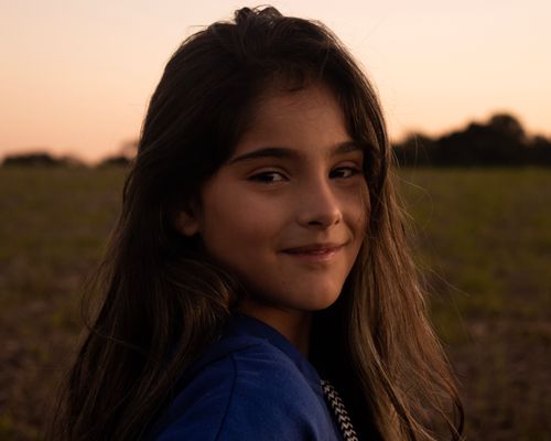 Free Beautiful portrait of a smiling girl outdoors during sunset, capturing a warm and serene moment. Stock Photo