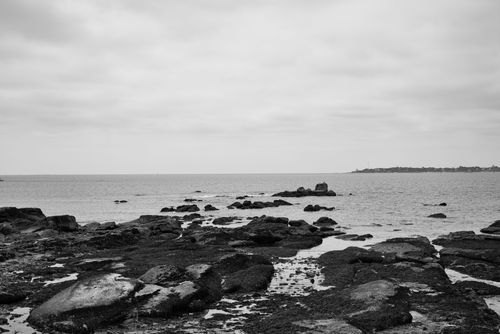 Free Black and white photo of rocky coastline under a cloudy sky, evoking a moody seascape. Stock Photo